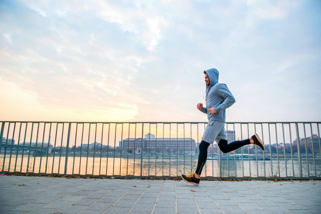 Man running on sidewalk in the early morning