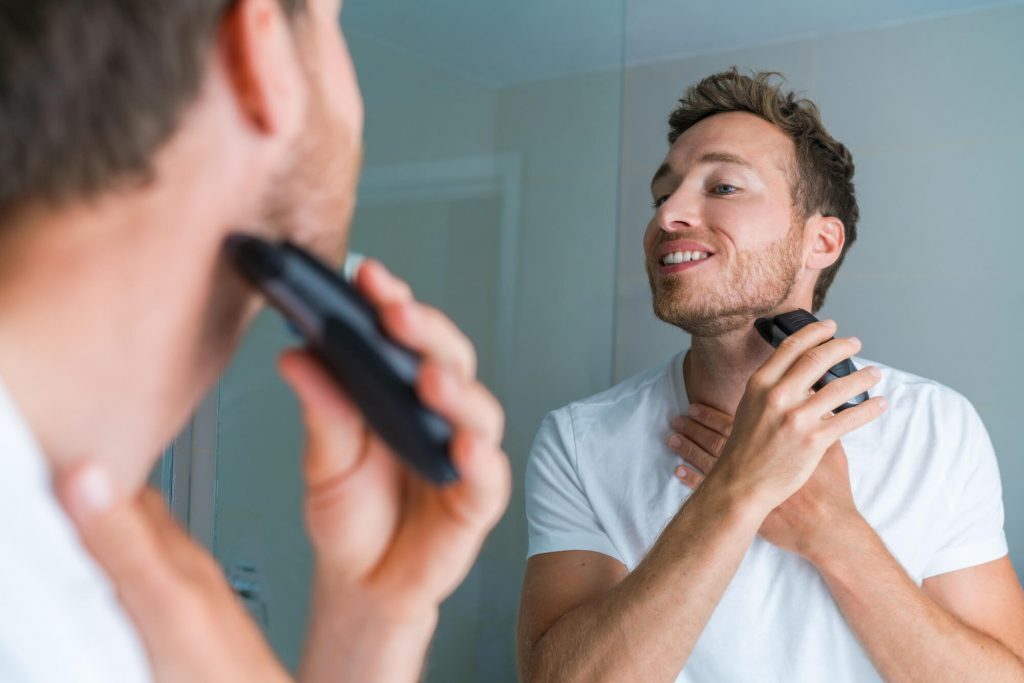 Man trimming his beard in mirror