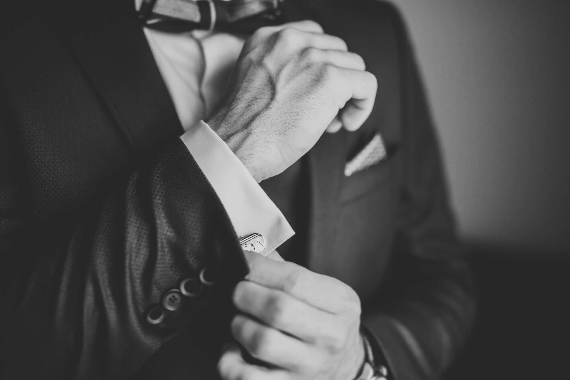 Man wearing a fancy tuxedo, adjusting cufflinks