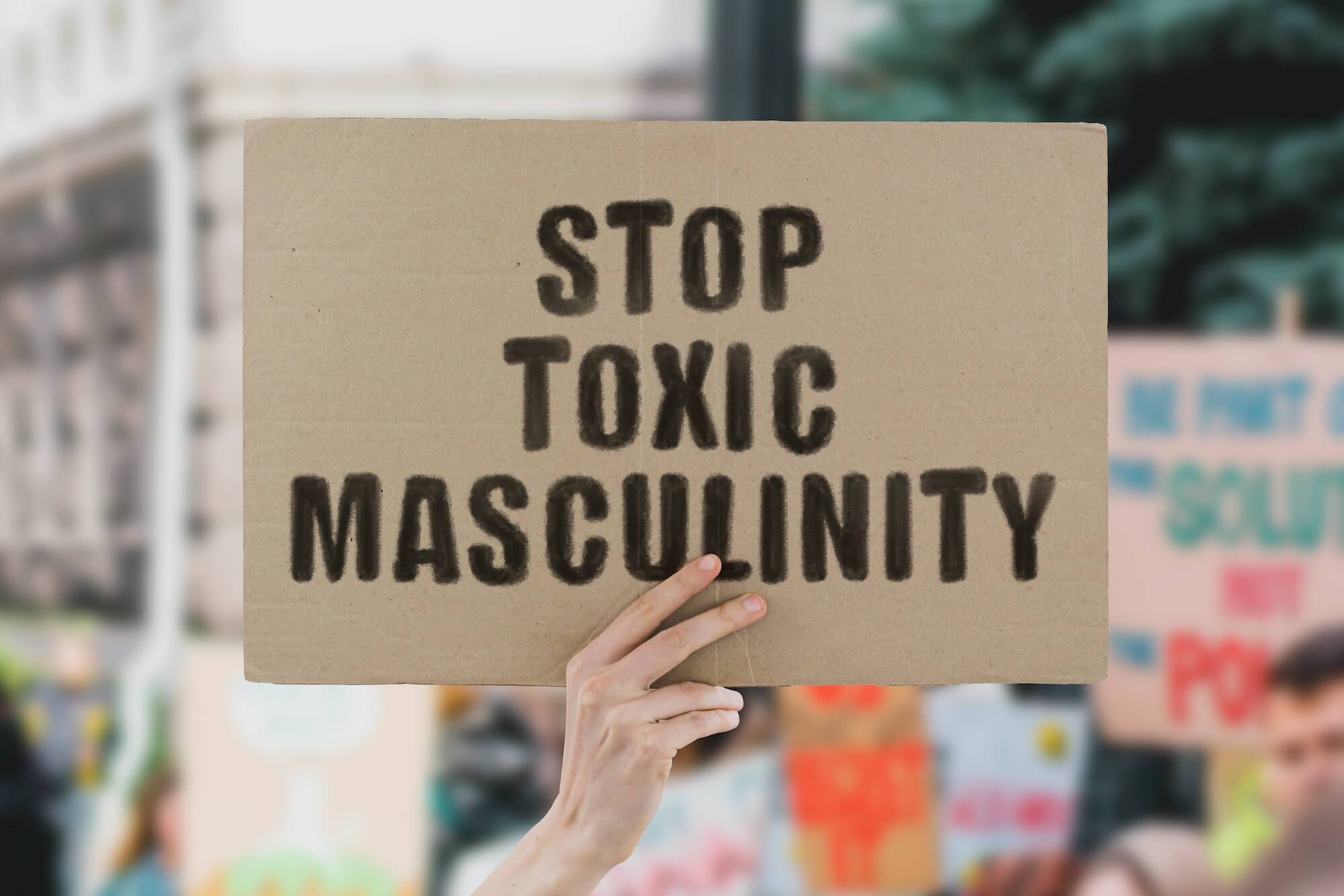 Man holding sign that says stop toxic masculinity