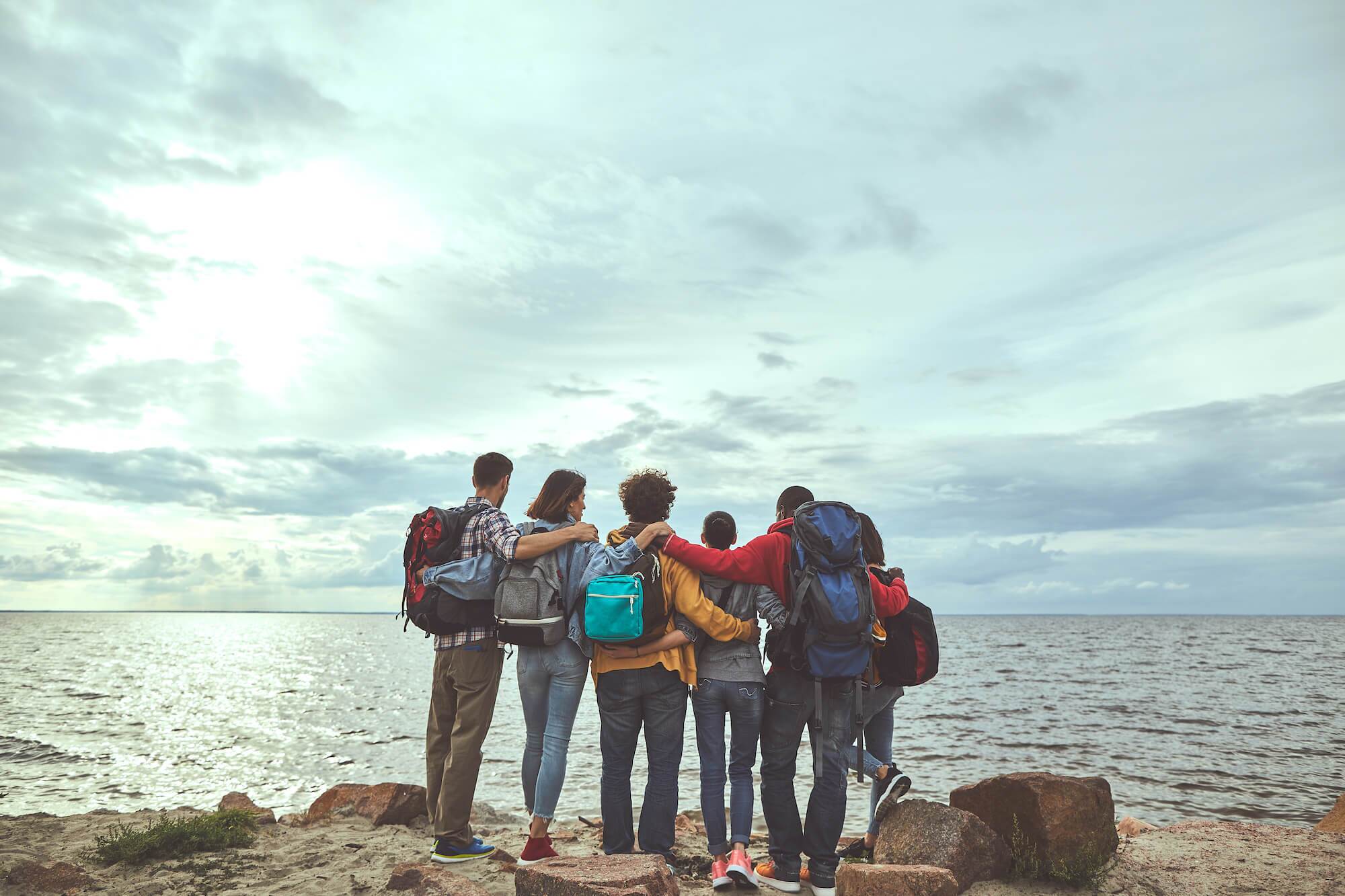 Gang of friends huddled together looking at the ocean