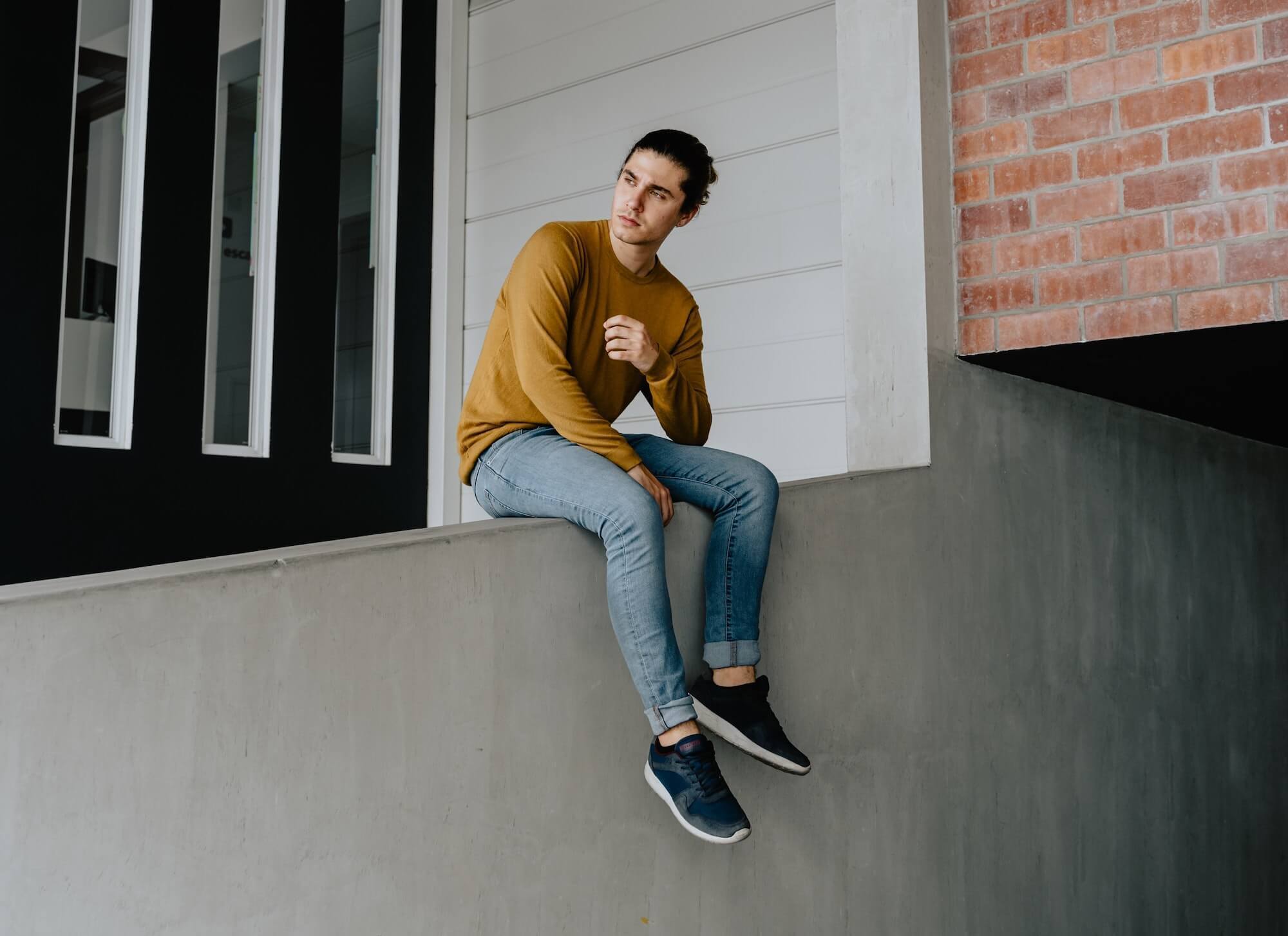 Man sitting on ledge in jeans and sneakers