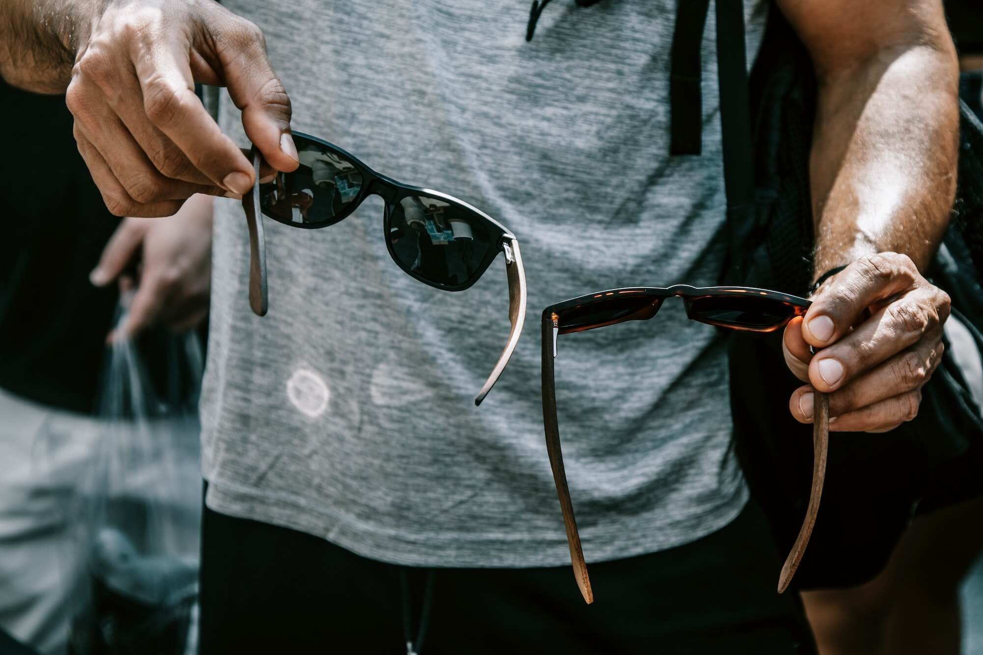 Man holding two pairs of sunglasses