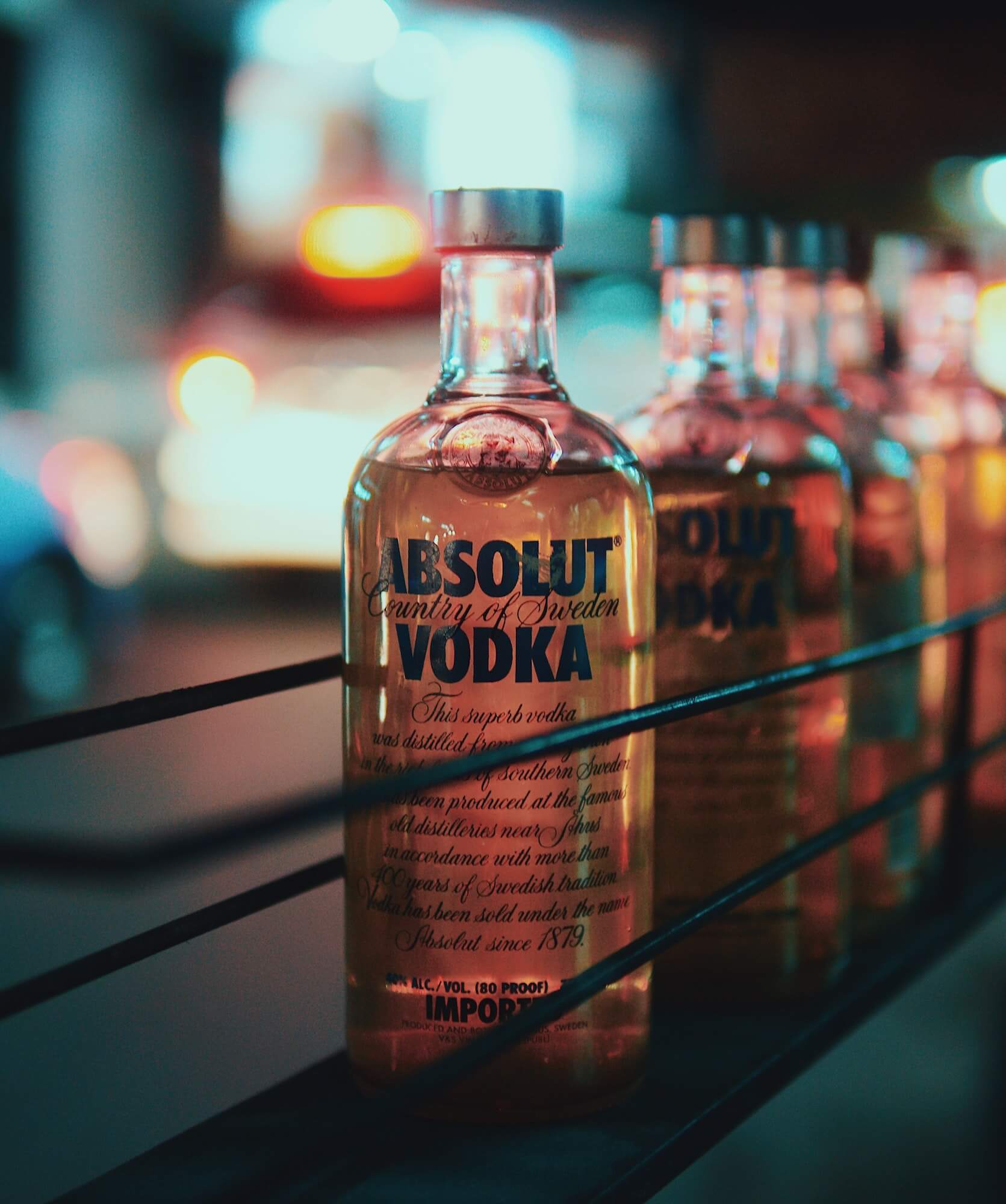 Row of Absolut vodka bottles with blurred bar background