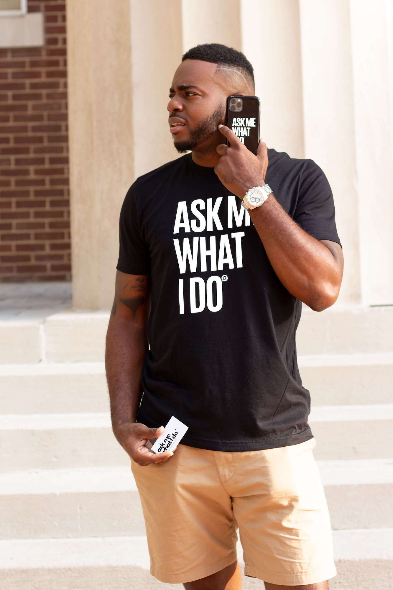 Young Black man wearing black and white "Ask me what I do" T-shirt