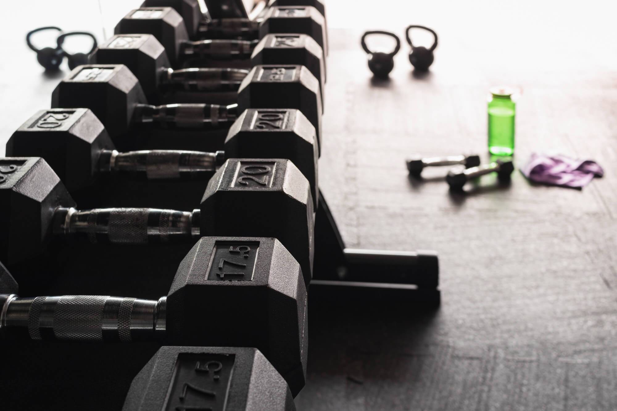 Row of free weights with water bottle and towel in the background
