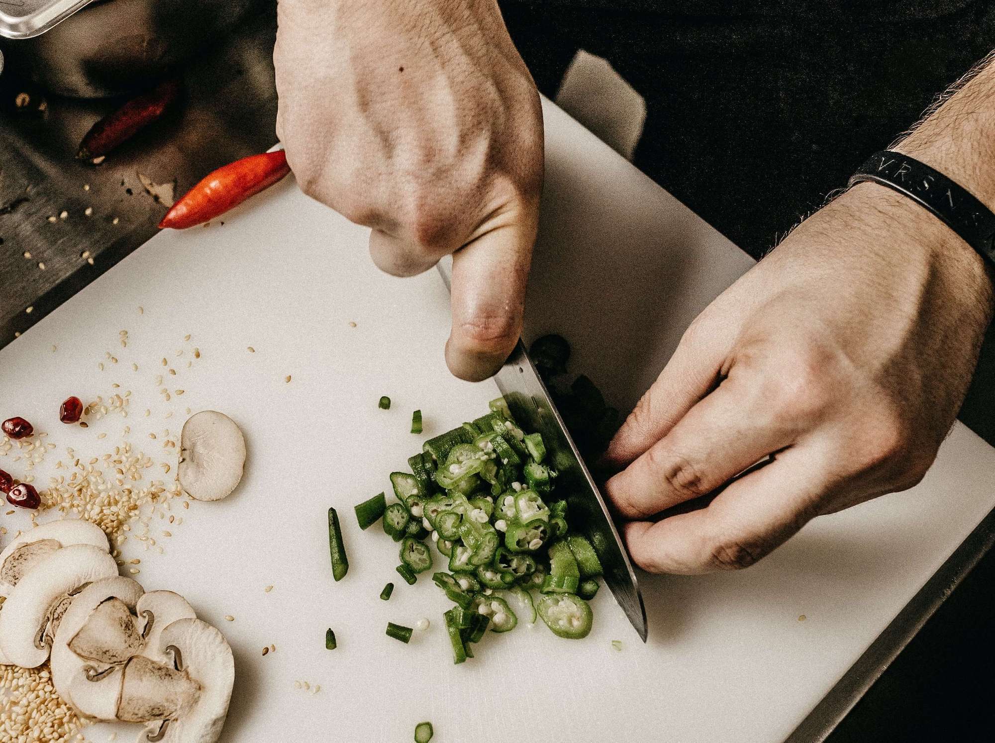 Man cutting peppers on cutting board with kitchen knife