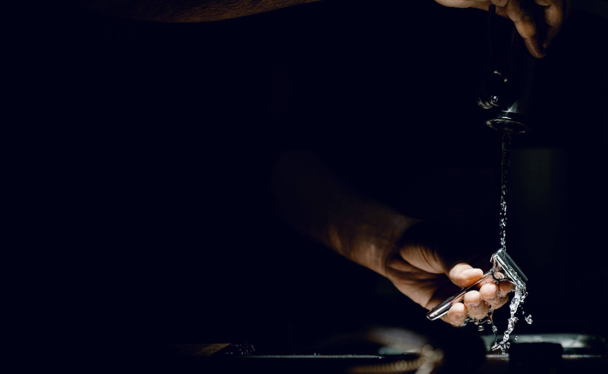 Spotlight on pair of hand rinsing a razor