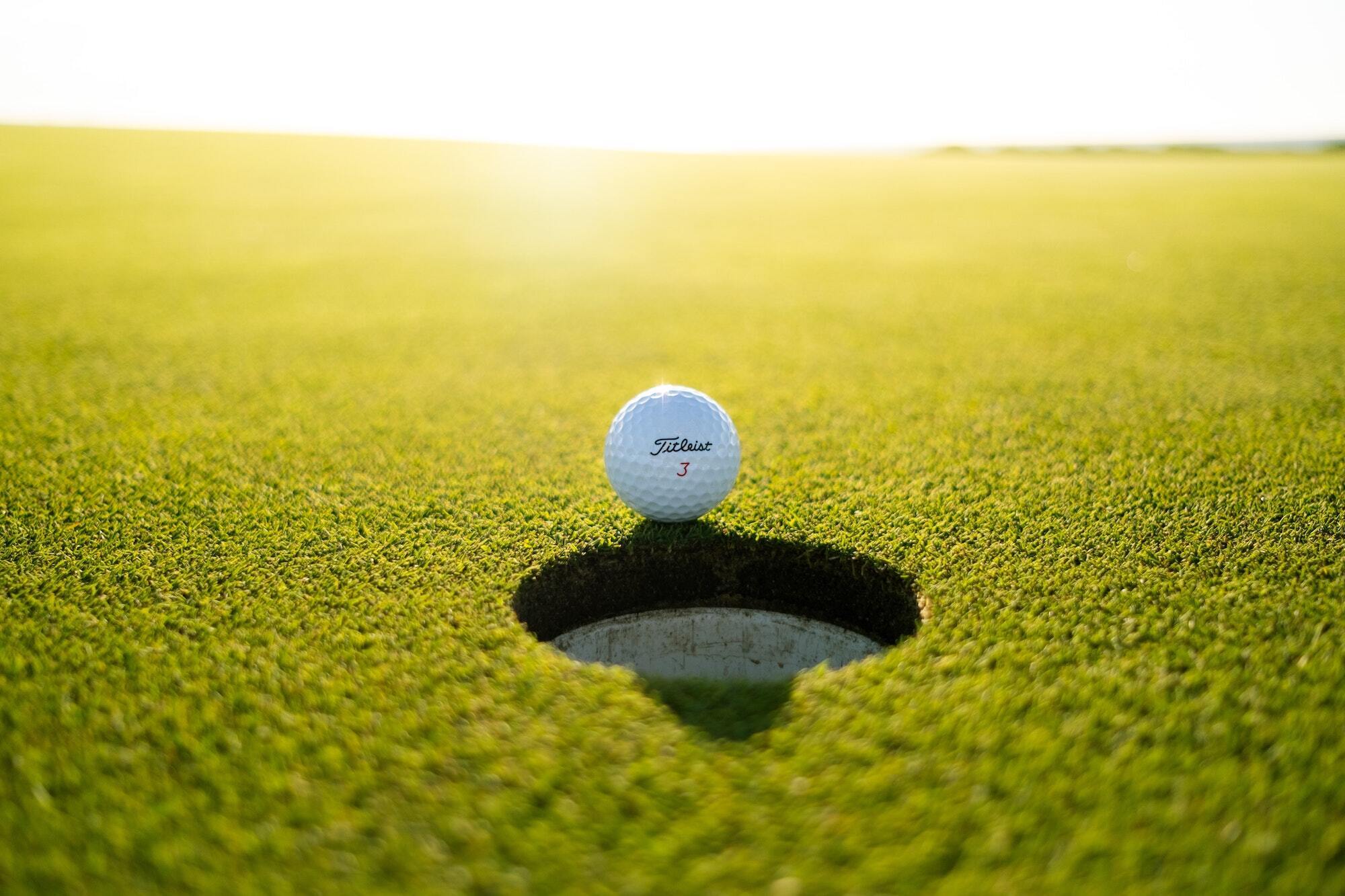 Titleist golf ball sits just outside the hole