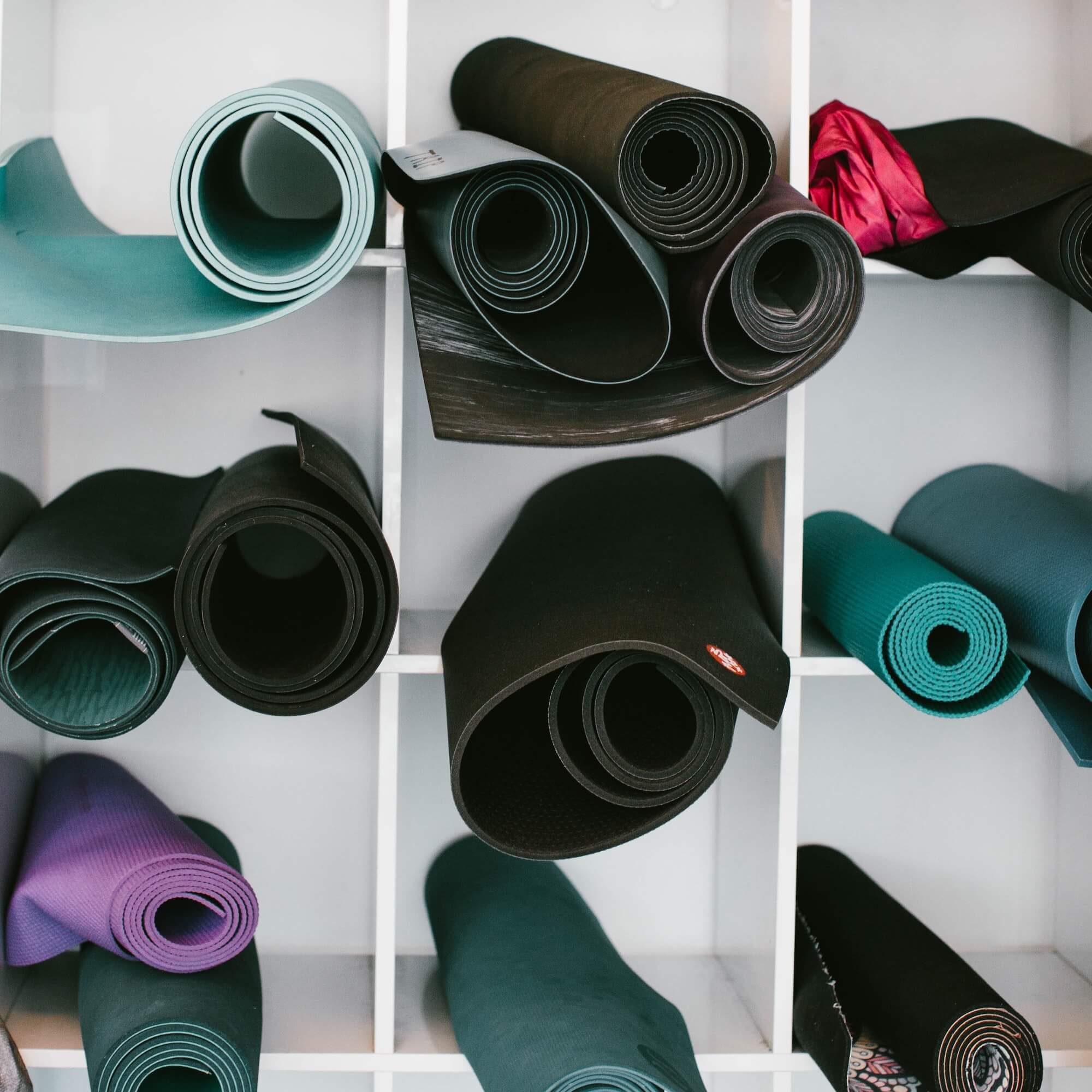 White shelving unit with a variety of rolled yoga mats in different colors