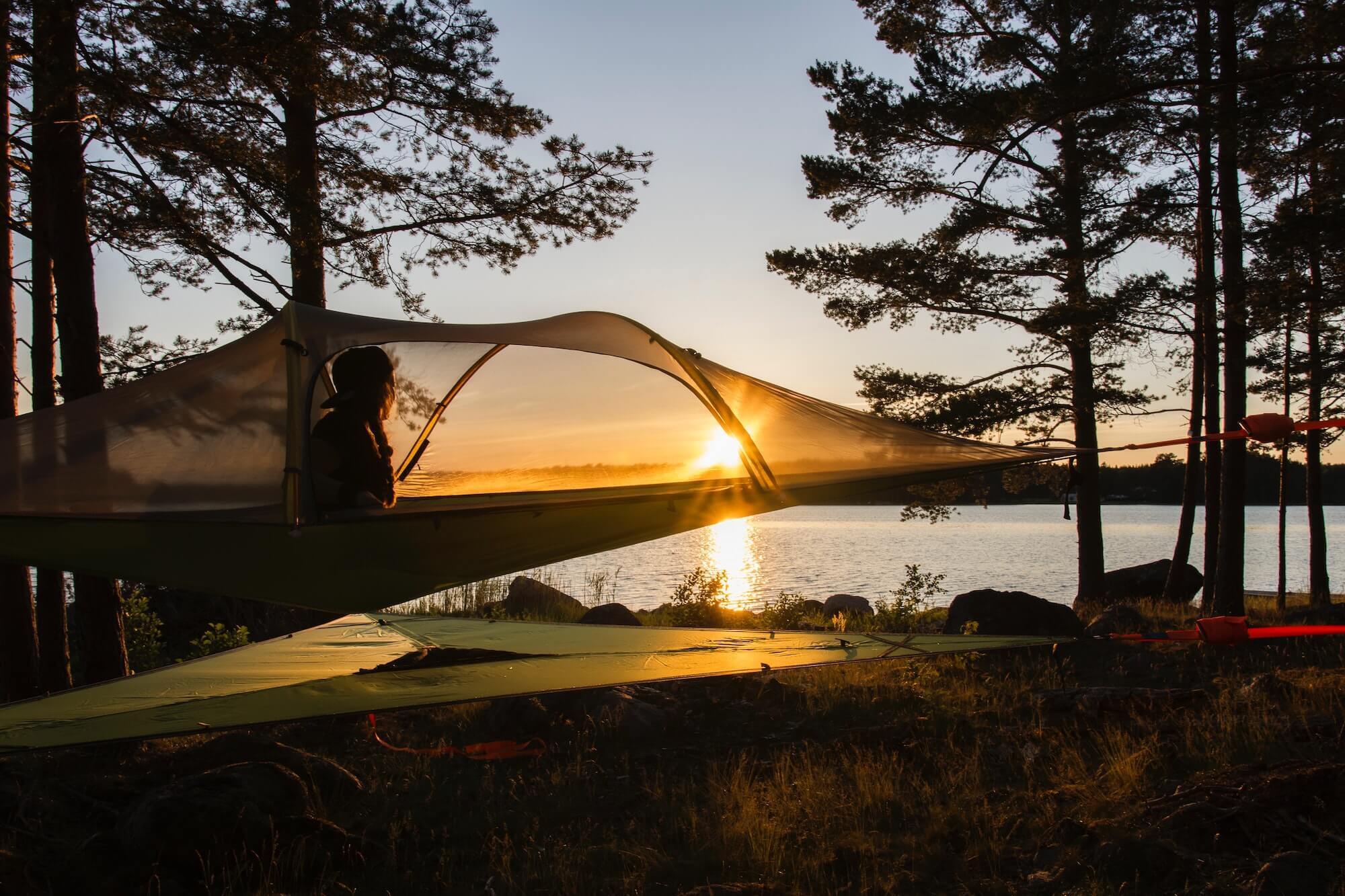 Person watching sunset from tree tent