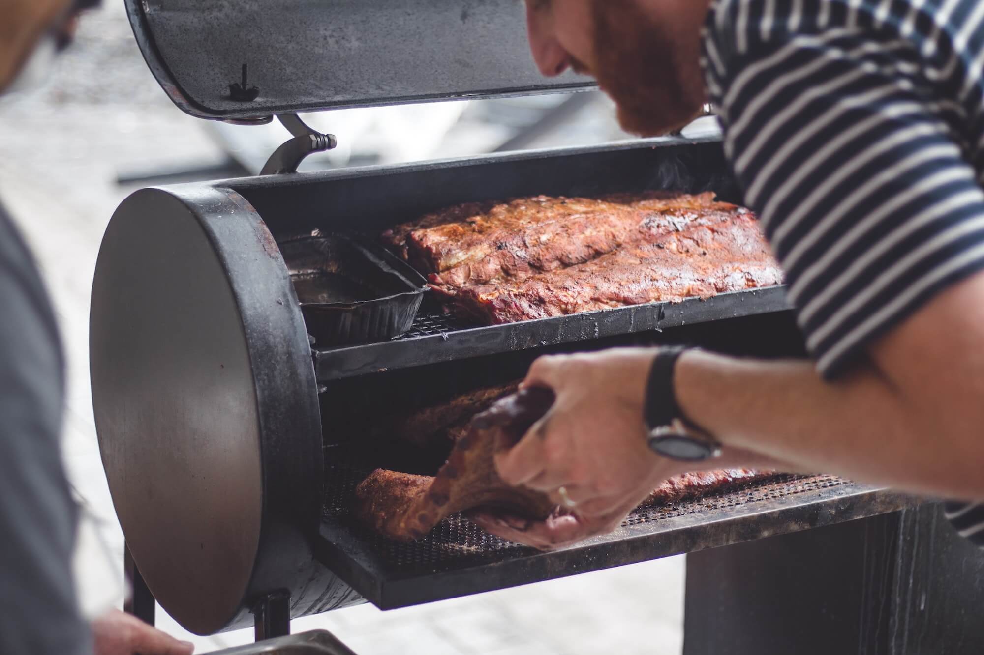 Man checking BBQ ribs in offset smoker