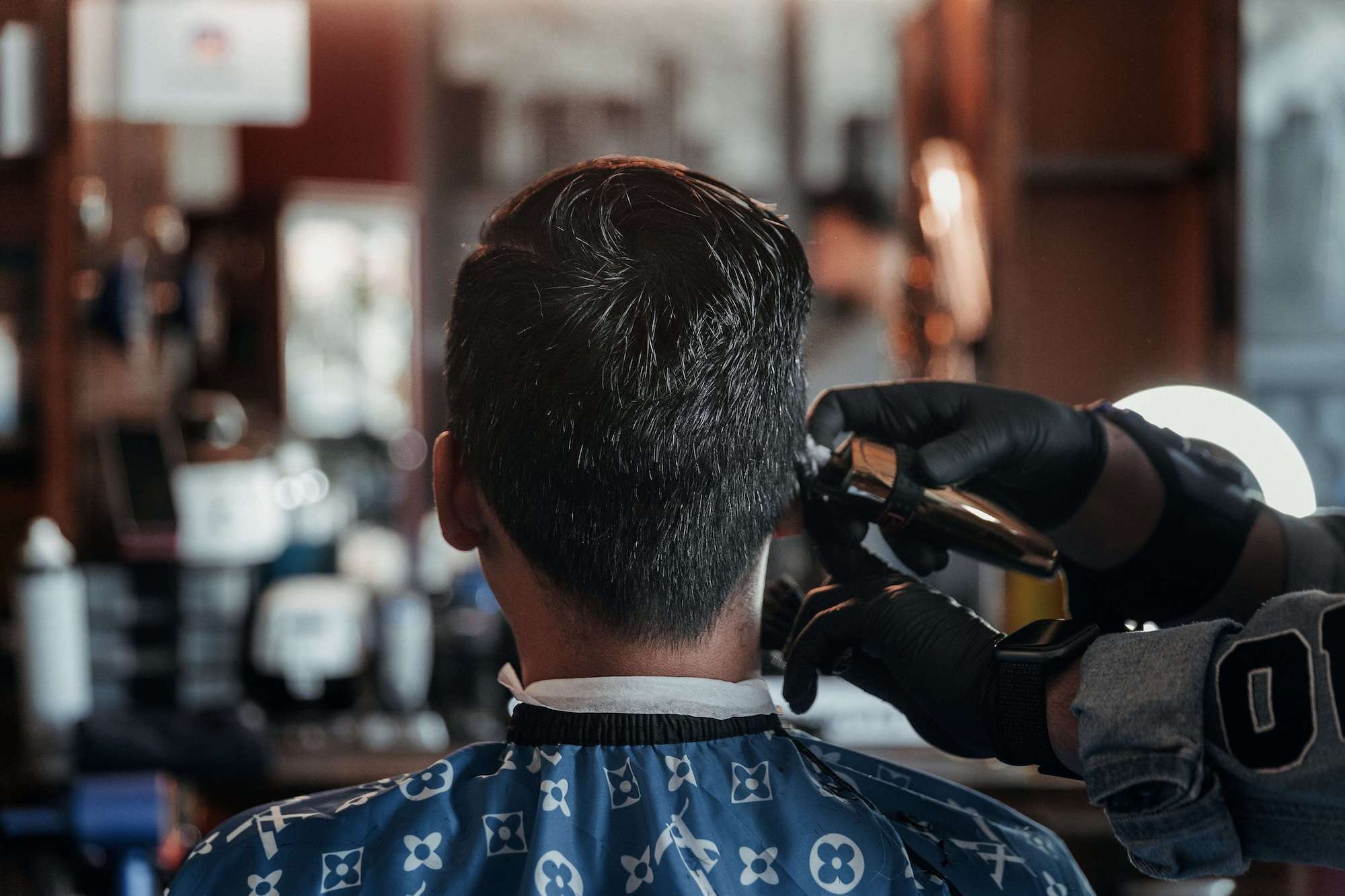 Man at barbershop getting haircut with cordless hair clippers