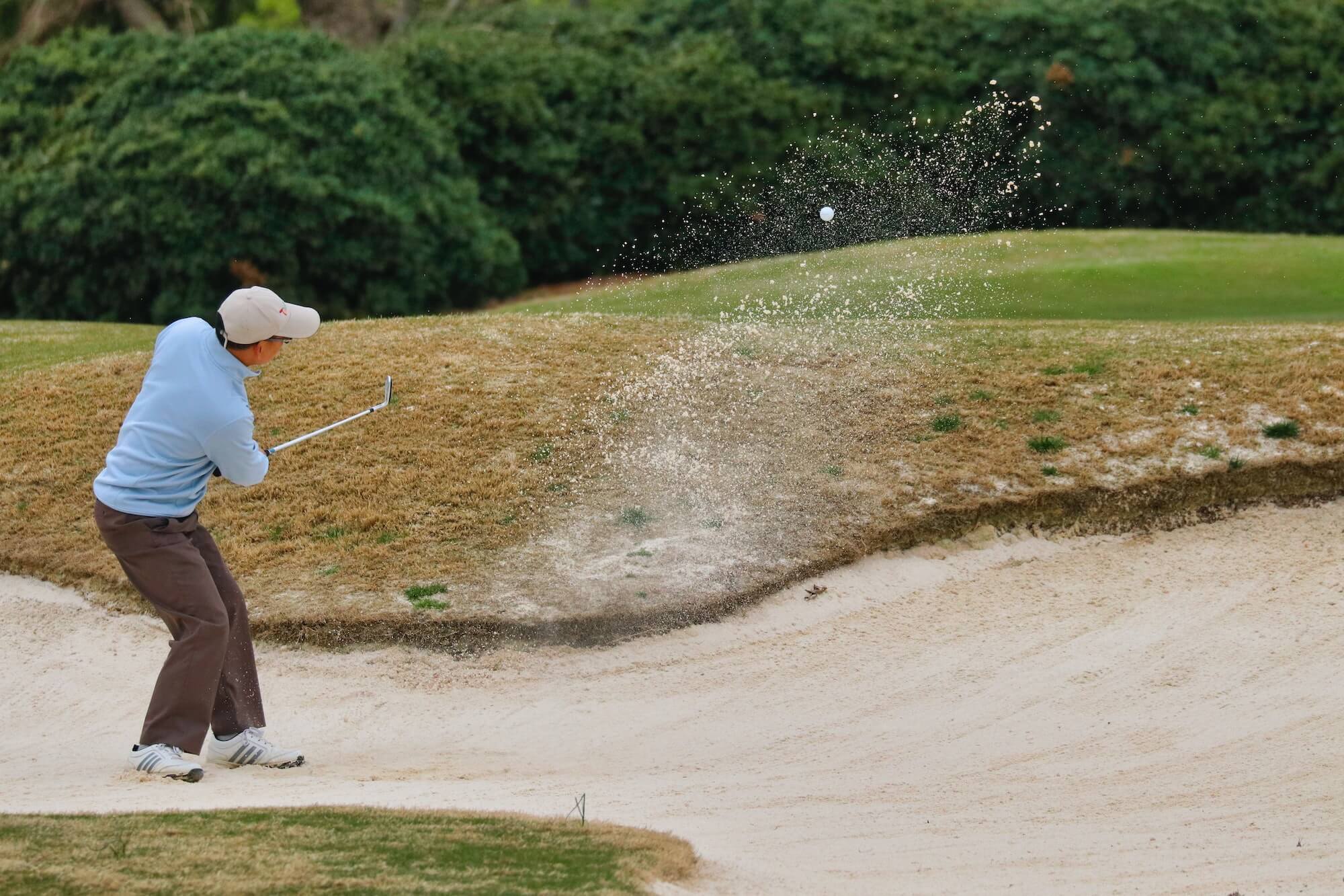 Man taking golf swing from the sand
